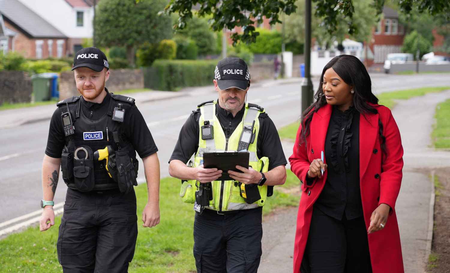 The Commissioner walking along pavement, accompanied by 2 police officers