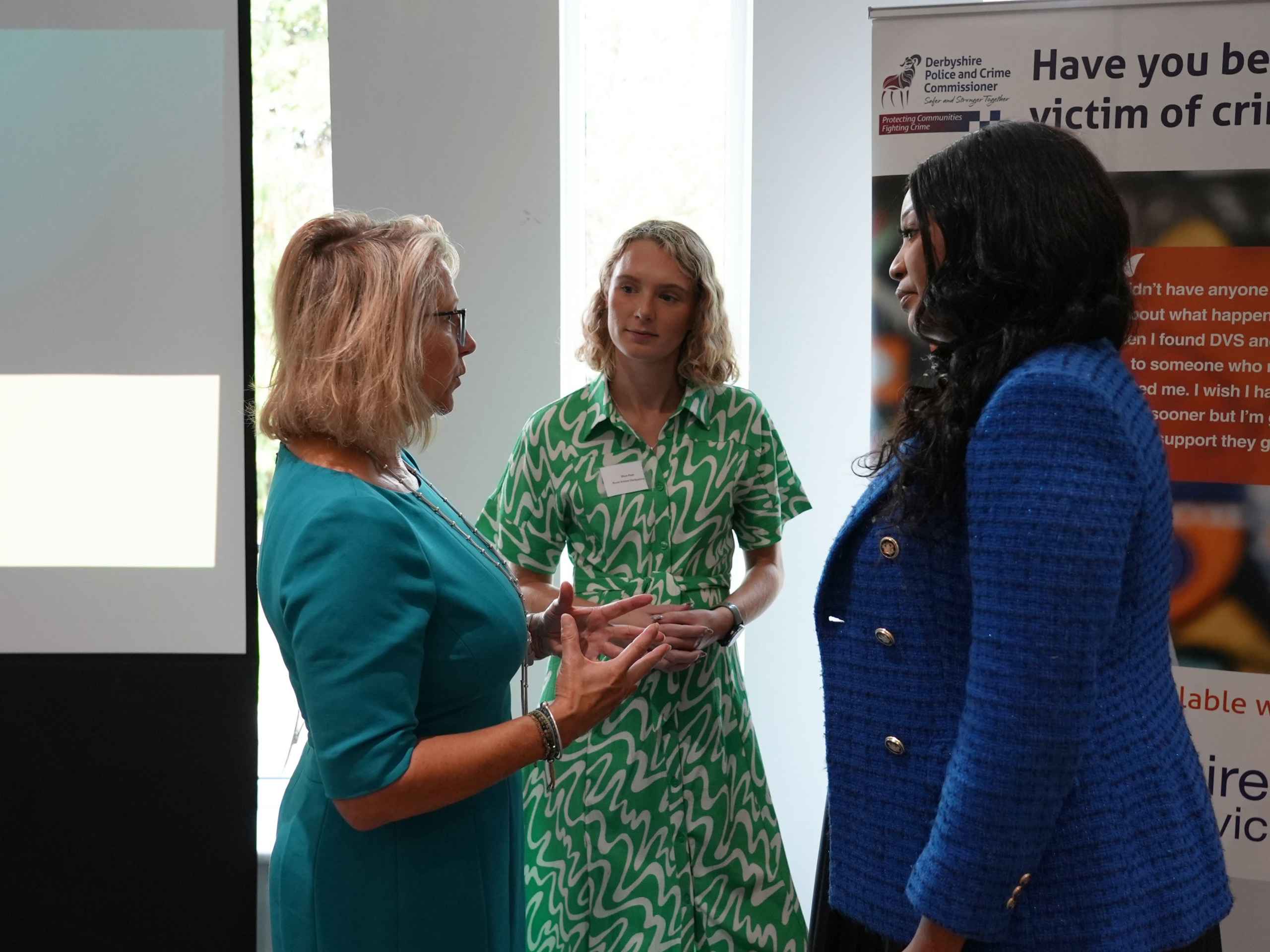 3042-DSC01503 Three women in from of a Victim of Crime banner