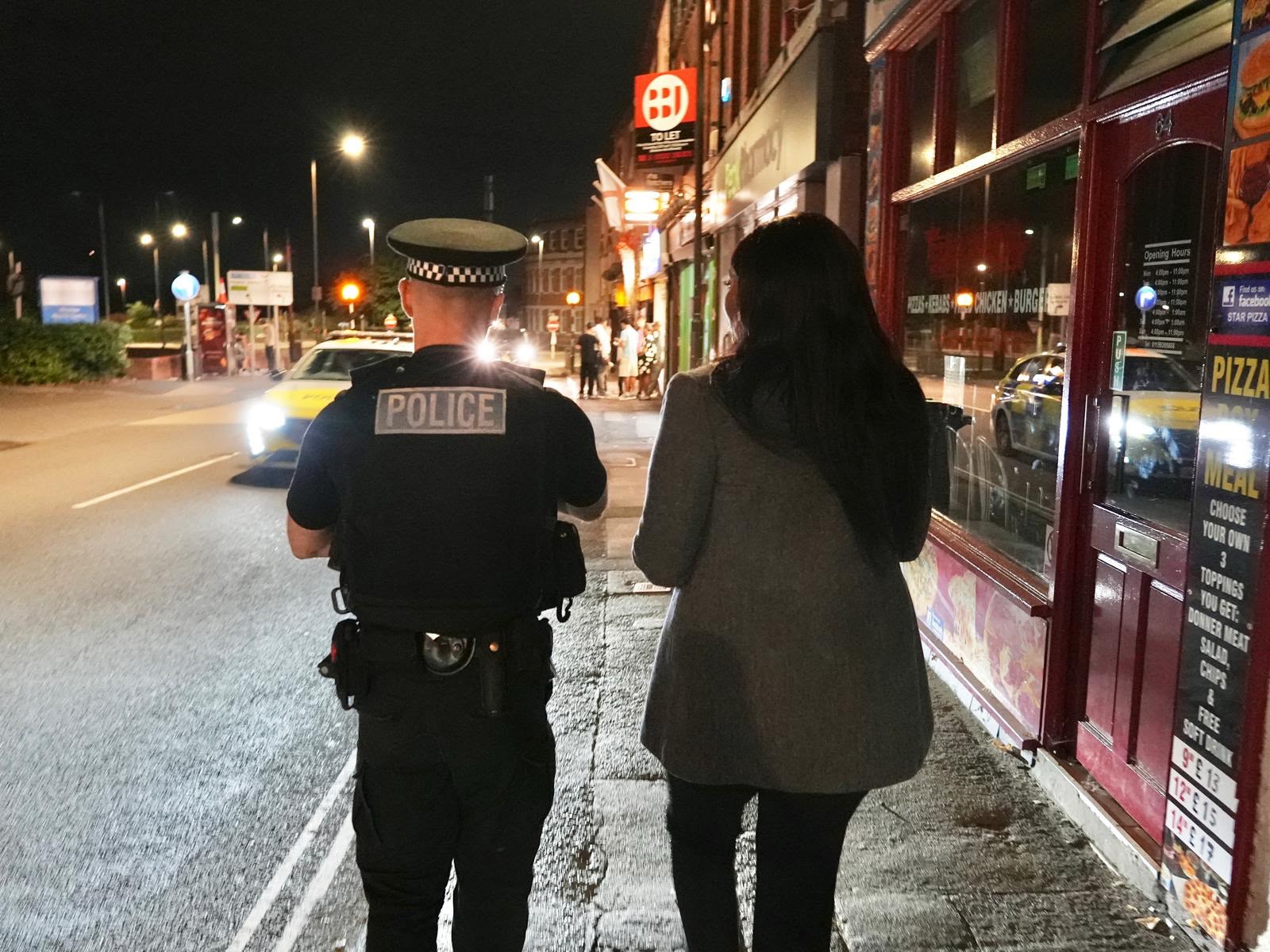 Commissioner and officer walking away down street at night