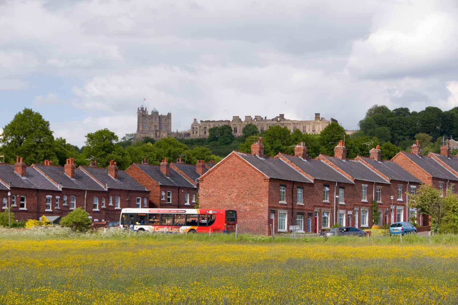 A shot of a bus travelling through Bolsover with houses and the castle in the background