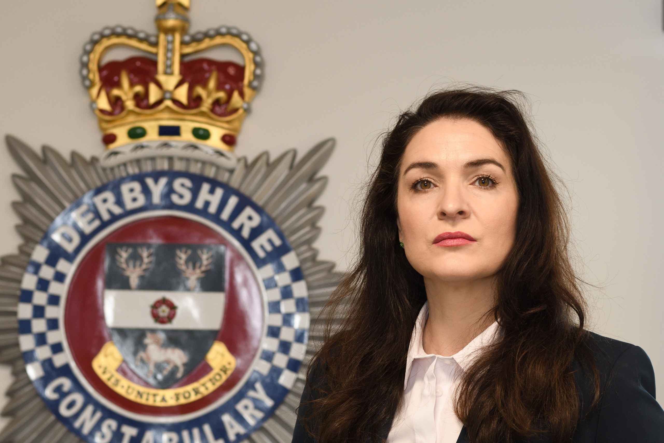 Commissioner in front of Derbyshire Police Crest