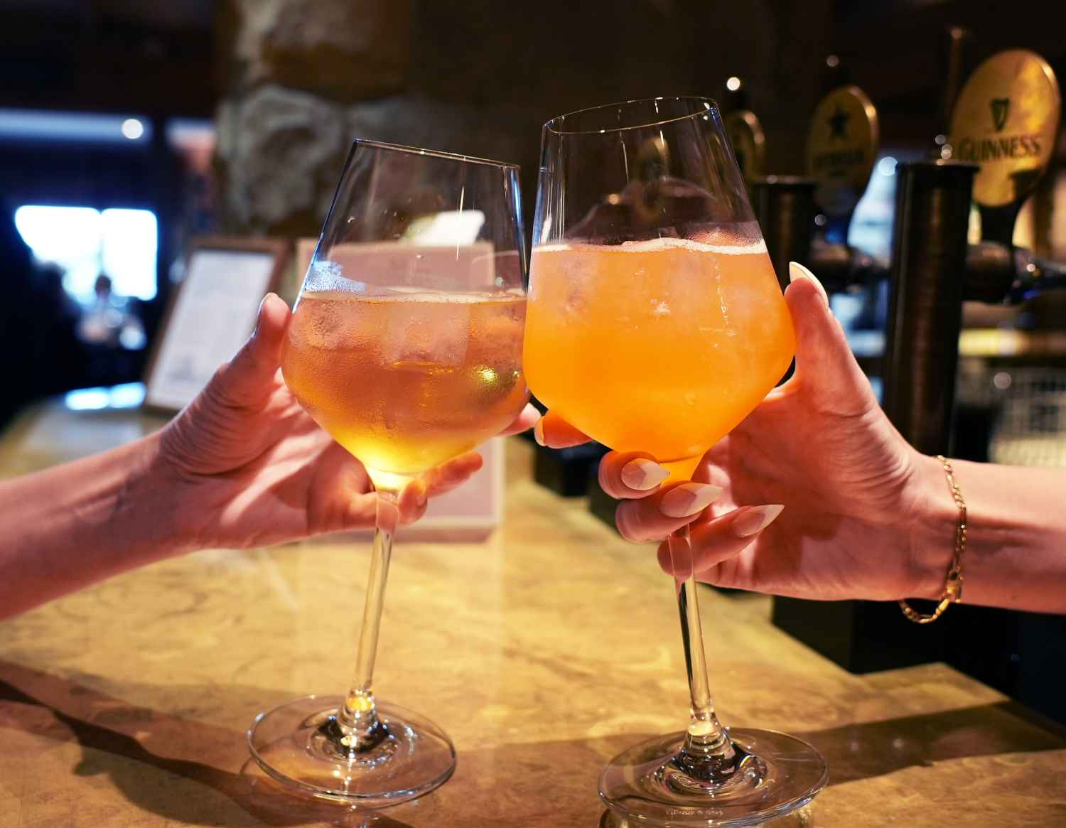 Two glasses containing cocktails being clinked together